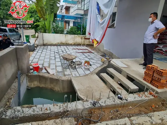 Thi Công Hồ Cá Koi Tinh Tế Với Đá Cuội Và Cây Xanh